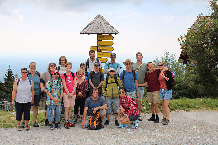 Gruppe der OBA-Teilnehmer steht auf einem Berg vor einem Wegweiser.