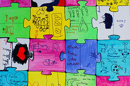 Ein von Schülern gemaltes Bild zeigt ein Puzzle aus bunten Teilen