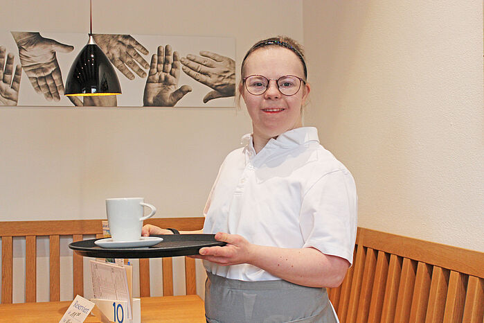 Mitarbeiterin das Cafes mit Tablett auf dem eine Tasse steht